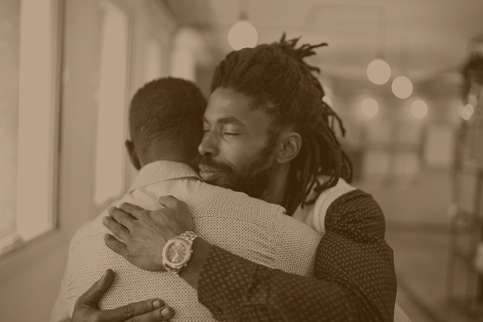 two african men hugging. peer-to-peer support